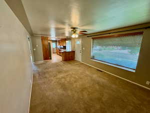 Unfurnished living room with light colored carpet and ceiling fan