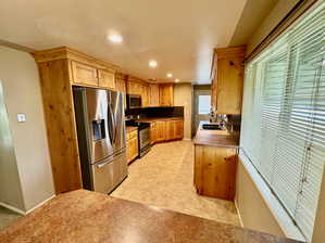 Kitchen featuring sink, backsplash, light tile floors, and stainless steel appliances