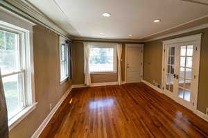 Spare room featuring french doors, dark wood-type flooring, and ornamental molding