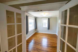 Empty room featuring french doors, crown molding, and hardwood / wood-style flooring