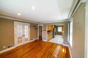 Unfurnished living room featuring ornamental molding, light hardwood / wood-style flooring, and french doors