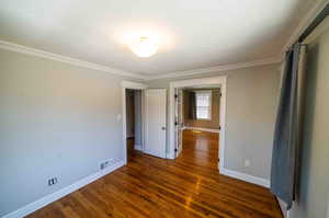 Spare room featuring dark hardwood / wood-style floors and ornamental molding