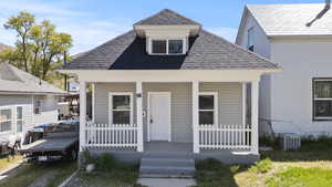View of front of house with a porch, a shingled roof, and central air condition unit