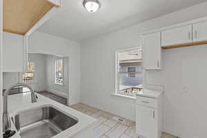 Kitchen featuring white cabinets, light stone countertops, visible vents, and a sink