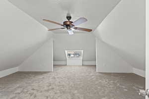 Bonus room with vaulted ceiling, carpet, and a ceiling fan