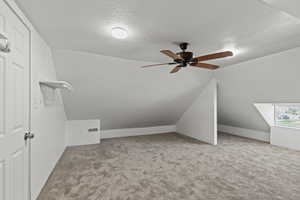 Additional living space with carpet, a ceiling fan, visible vents, and a textured ceiling