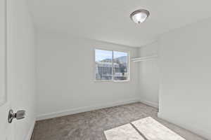 Unfurnished room with carpet floors, a textured ceiling, and baseboards