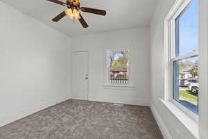 Spare room with carpet, visible vents, a ceiling fan, and baseboards
