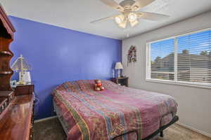 Bedroom featuring a textured ceiling, carpet, and ceiling fan