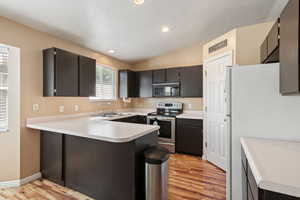 Kitchen with kitchen peninsula, electric stove, light wood-type flooring, and white refrigerator