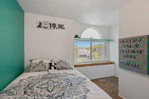 Bedroom with dark colored carpet and a textured ceiling