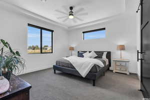 Bedroom with dark carpet, ceiling fan, and a raised ceiling