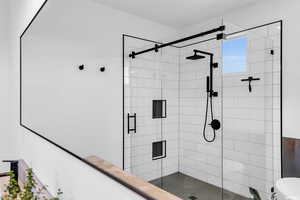 Bathroom featuring a shower with door and toilet