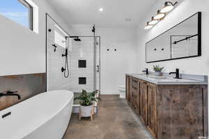 Full bathroom featuring dual vanity, concrete flooring, toilet, and independent shower and bath