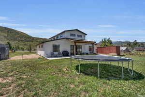 Back of property featuring a patio area, a mountain view, a lawn, and a trampoline