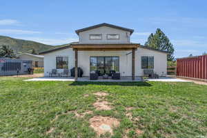 Back of house featuring a lawn, an outdoor living space, and a patio