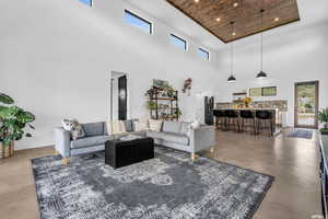 Living room featuring a healthy amount of sunlight, wooden ceiling, a towering ceiling, and concrete flooring