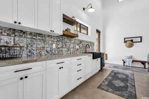 Kitchen with sink, concrete flooring, backsplash, and white cabinetry