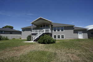 Back of house with a deck and a yard