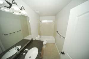 Full bathroom featuring tiled shower / bath, tile flooring, toilet, and large vanity