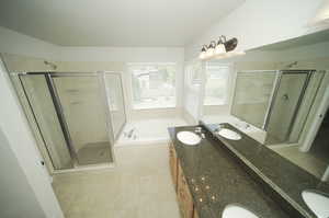 Bathroom featuring shower with separate bathtub, double sink vanity, and tile floors