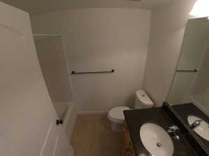 Full bathroom with washtub / shower combination, tile flooring, vanity with extensive cabinet space, and toilet