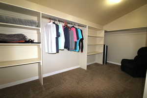 Walk in closet featuring dark colored carpet and lofted ceiling