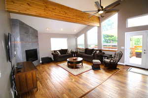 Living room with ceiling fan, a high ceiling, bamboo style flooring,