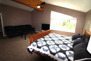 The bedroom features an ensuite bath, a walk-in closet, a lofted ceiling with beams, and a ceiling fan.