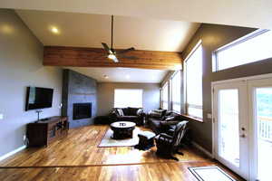 Living room with ceiling fan, a high ceiling, bamboo style flooring,