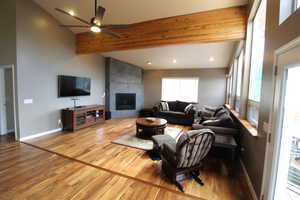 Living room with ceiling fan, a high ceiling, bamboo style flooring,