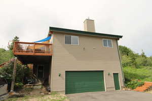 Back of house featuring a garage and a deck