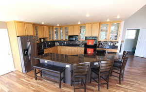 Kitchen with dark granite countertops, wood-style floors, tasteful backsplash, and a center island