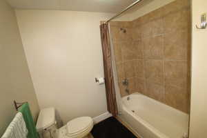 Bathroom featuring shower / bath combination with curtain and toilet