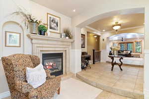 Tiled living room featuring ceiling fan, ornamental molding, and a tile fireplace