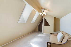 Additional living space featuring vaulted ceiling with skylight, a textured ceiling, carpet floors, and ceiling fan