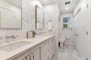 Bathroom with double vanity, toilet, and tile floors