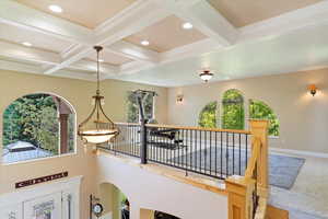 Loft with a wealth of natural light, coffered ceiling, and beam ceiling