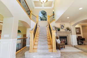 Stairs with a high ceiling, ornamental molding, light tile flooring, and a high end fireplace