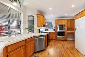 Kitchen with light hardwood / wood-style floors, sink, tasteful backsplash, and stainless steel appliances