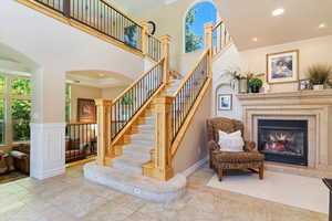 Staircase with tile flooring,  fireplace, crown molding, ornate columns, and a towering ceiling