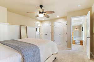 Carpeted bedroom featuring two closets and ceiling fan