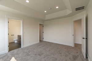 Unfurnished bedroom featuring dark colored carpet and connected bathroom