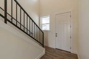 Foyer entrance with a towering ceiling and dark hardwood / wood-style flooring