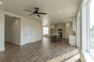 Kitchen with wood-type flooring, a kitchen island, sink, ceiling fan, and appliances with stainless steel finishes