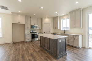 Kitchen featuring a kitchen island, stainless steel appliances, sink, and dark hardwood / wood-style floors