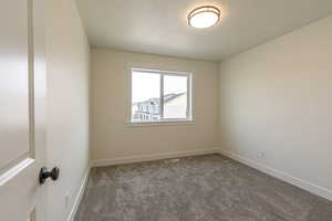 Empty room with carpet flooring and a textured ceiling