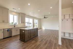 Kitchen with dishwasher, sink, dark wood-type flooring, ceiling fan, and a kitchen island