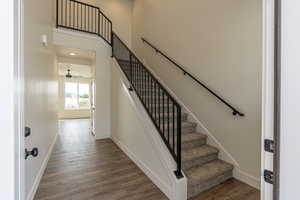 Staircase featuring ceiling fan, a towering ceiling, and hardwood / wood-style flooring