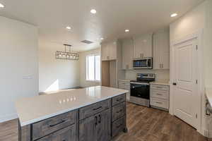 Kitchen featuring a kitchen island, stainless steel appliances, dark hardwood / wood-style floors, and light stone countertops